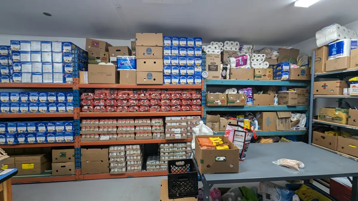 Food bank pantry shelves stocked with canned goods and paper products
